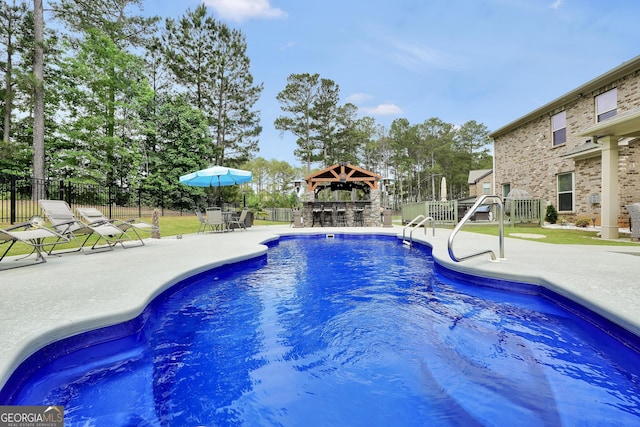 view of swimming pool with a patio area, outdoor dry bar, a gazebo, fence, and a fenced in pool