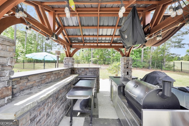 view of patio / terrace featuring a sink, exterior kitchen, a fenced backyard, and a grill
