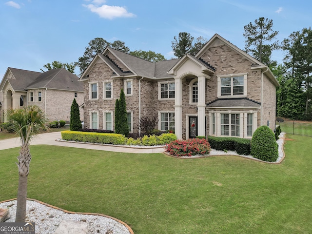view of front facade featuring fence, brick siding, and a front yard