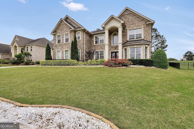 view of front of home with brick siding, fence, and a front lawn