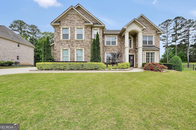 view of front of home featuring central air condition unit, brick siding, and a front yard