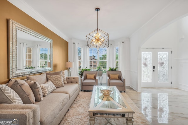 living area featuring crown molding, a notable chandelier, arched walkways, french doors, and baseboards