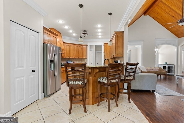 4577 San Saba Dr, Hahira, GA 31632 - kitchen featuring crown molding, a peninsula, open floor plan, a kitchen bar, and stainless steel fridge