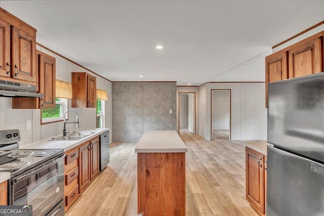 kitchen featuring light wood-style floors, a center island, under cabinet range hood, a sink, and stainless steel appliances