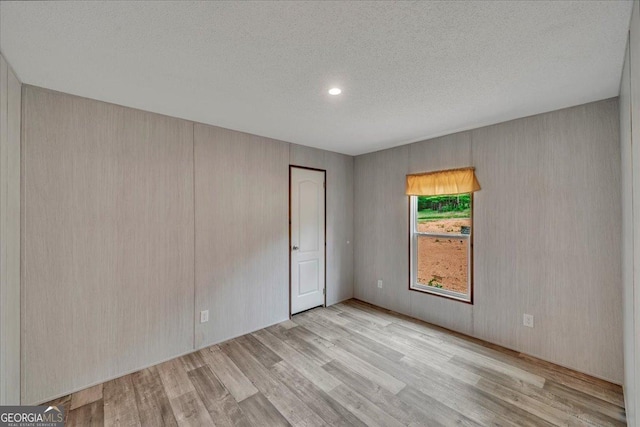 empty room featuring a textured ceiling, recessed lighting, and wood finished floors
