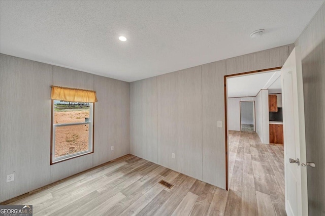 unfurnished room with visible vents, a textured ceiling, and wood finished floors