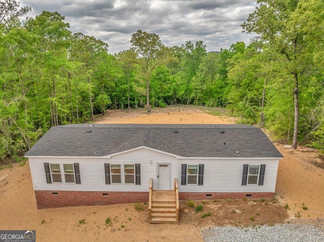 view of front of house featuring a view of trees, roof with shingles, and crawl space
