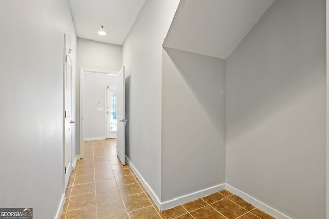 corridor with baseboards and tile patterned flooring