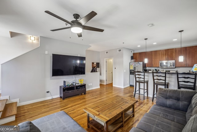 living area featuring baseboards, a ceiling fan, recessed lighting, and light wood-style flooring