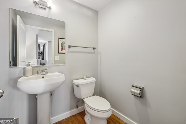bathroom with a sink, baseboards, toilet, and wood finished floors