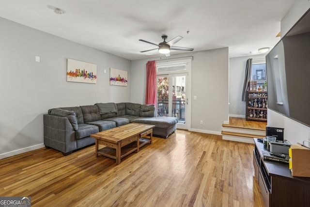 living room featuring baseboards, light wood-style flooring, and ceiling fan