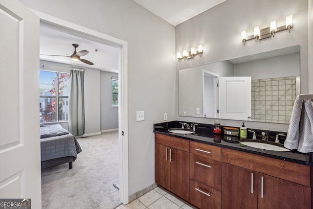ensuite bathroom featuring baseboards, double vanity, a ceiling fan, and a sink