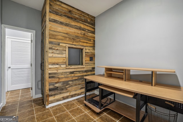 dining space featuring dark tile patterned floors, baseboards, and wood walls