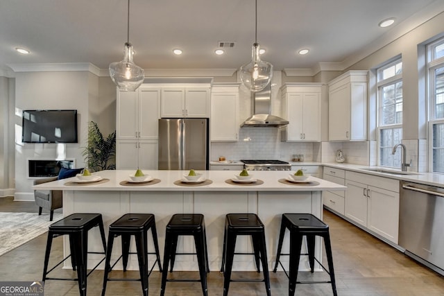 606 Broadview Ter NE, Atlanta, GA 30324 - kitchen with wall chimney range hood, crown molding, appliances with stainless steel finishes, a sink, and white cabinetry