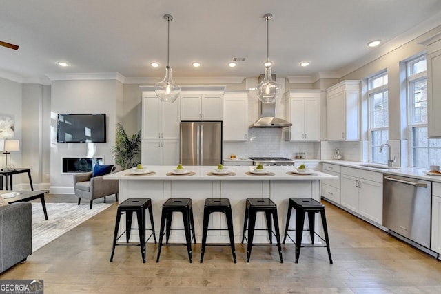 606 Broadview Ter NE, Atlanta, GA 30324 - kitchen with wall chimney range hood, a kitchen breakfast bar, crown molding, appliances with stainless steel finishes, and a sink