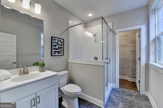 606 Broadview Ter NE, Atlanta, GA 30324 - bathroom featuring vanity, toilet, baseboards, a walk in closet, and a stall shower