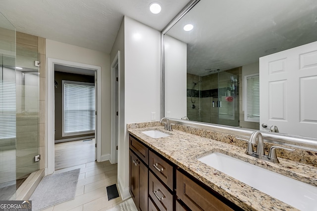 full bathroom with visible vents, a sink, a stall shower, and double vanity