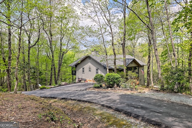 view of side of home with a chimney and aphalt driveway