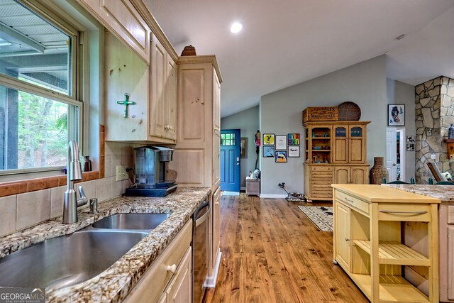 kitchen featuring a sink, light wood-style flooring, backsplash, and lofted ceiling