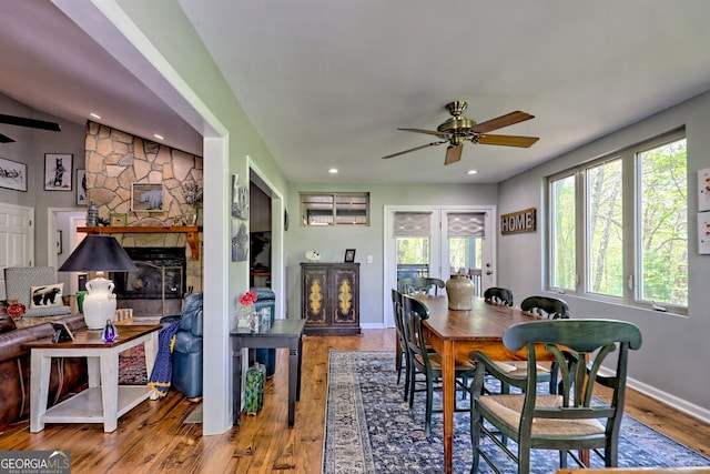 dining area with a stone fireplace, a ceiling fan, baseboards, recessed lighting, and wood finished floors