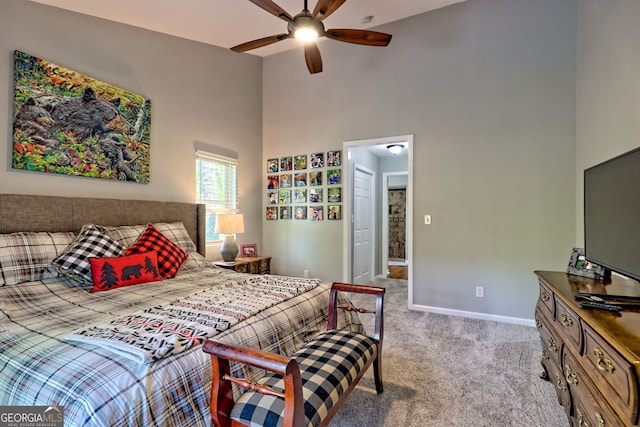 carpeted bedroom featuring baseboards, ceiling fan, and a high ceiling
