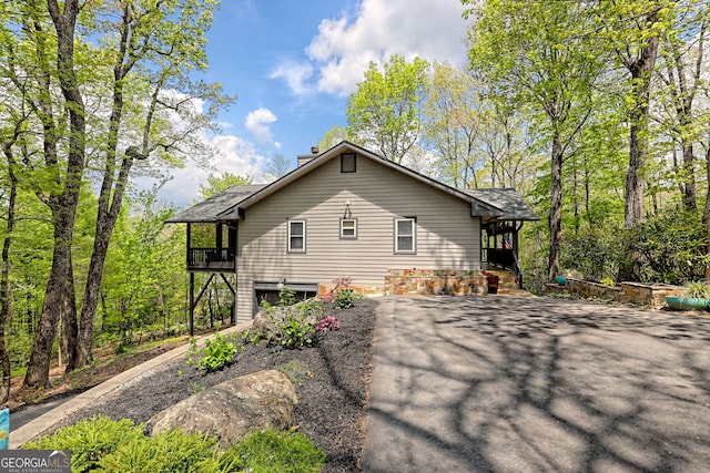 view of side of home featuring a chimney and aphalt driveway