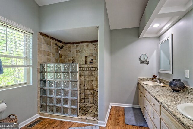 full bath with walk in shower, a sink, a wealth of natural light, wood finished floors, and visible vents