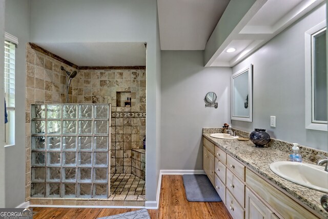full bath featuring a walk in shower, a sink, double vanity, baseboards, and wood finished floors