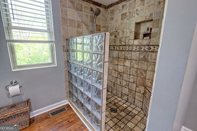 bathroom featuring walk in shower, baseboards, visible vents, and wood finished floors