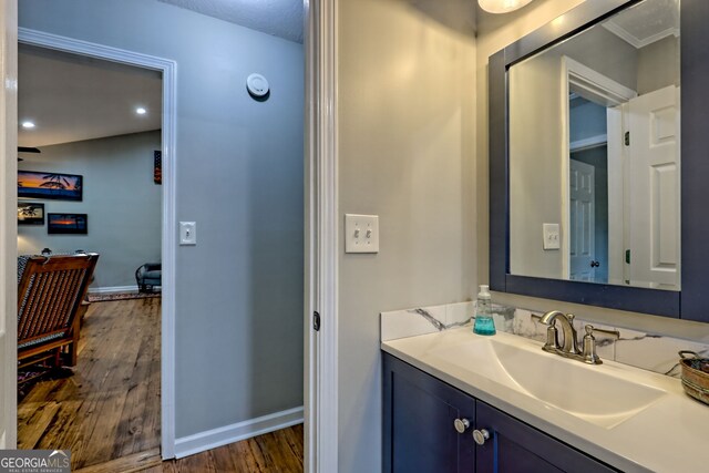 bathroom with baseboards, recessed lighting, wood finished floors, and vanity
