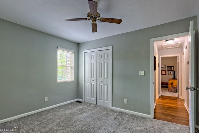 unfurnished bedroom with ceiling fan, carpet floors, attic access, baseboards, and a closet