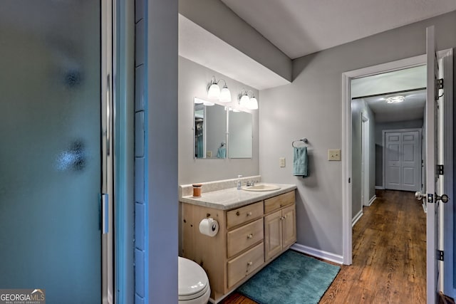 bathroom with toilet, baseboards, wood finished floors, and vanity