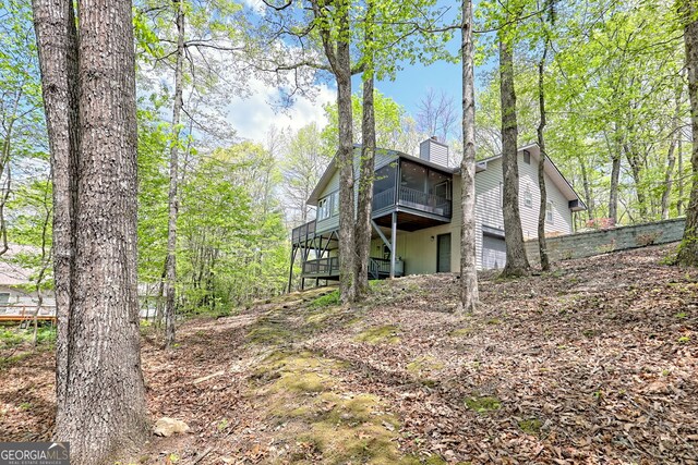 rear view of property with a sunroom, a chimney, and a deck
