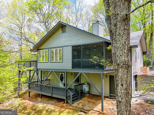 rear view of house with a chimney and a sunroom