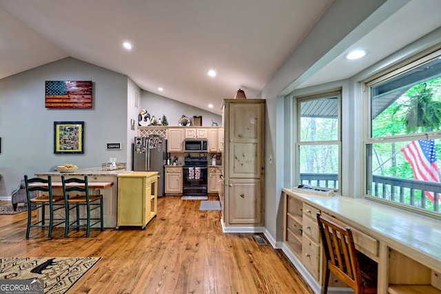 kitchen featuring light wood-style floors, stainless steel appliances, a kitchen bar, a kitchen island, and vaulted ceiling