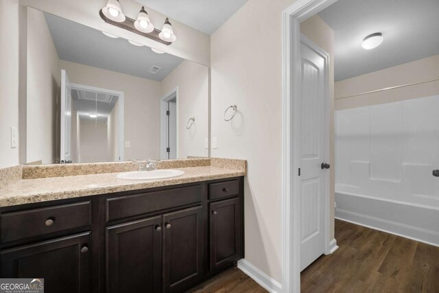 bathroom featuring vanity, shower / bath combination, baseboards, and wood finished floors