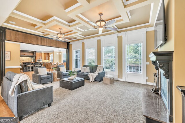 living room with a fireplace, a ceiling fan, ornamental molding, and coffered ceiling