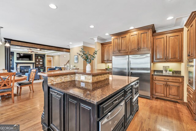 kitchen with crown molding, built in appliances, brown cabinets, light wood finished floors, and a warming drawer