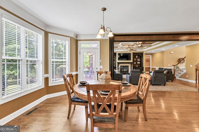 dining area featuring crown molding, baseboards, a glass covered fireplace, and wood finished floors