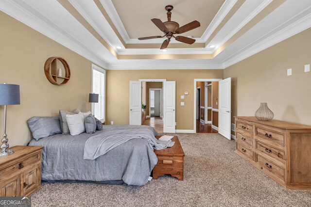 carpeted bedroom featuring baseboards, a tray ceiling, ornamental molding, and ceiling fan
