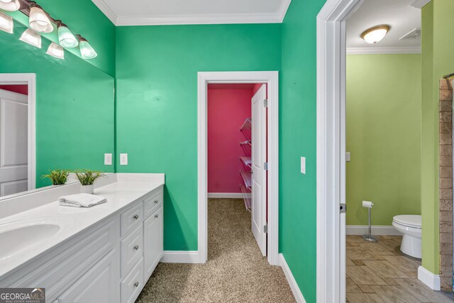 bathroom featuring visible vents, ornamental molding, vanity, toilet, and baseboards