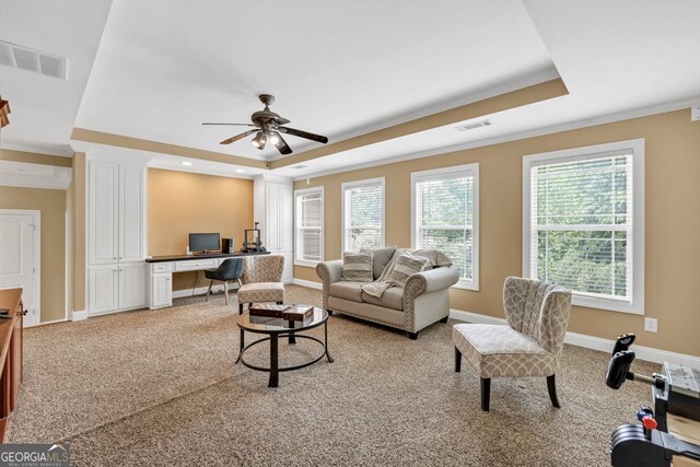 carpeted living room with crown molding, ceiling fan, visible vents, and a raised ceiling