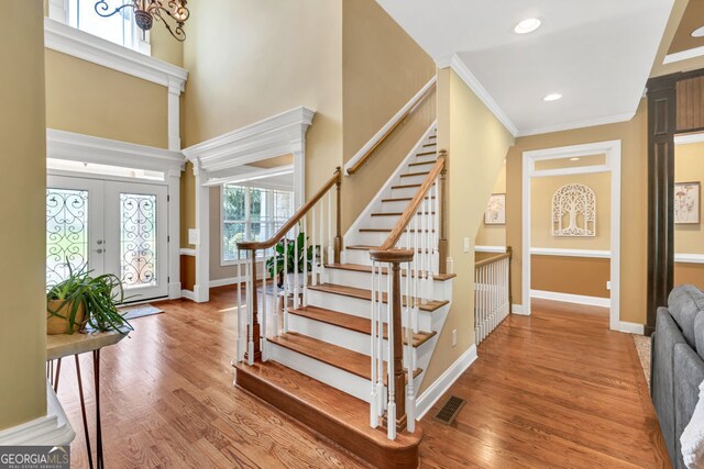entrance foyer featuring baseboards, wood finished floors, a towering ceiling, visible vents, and stairway