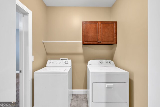 clothes washing area featuring washer and dryer, baseboards, and cabinet space