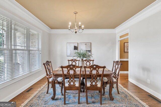 dining space featuring a chandelier, ornamental molding, and wood finished floors