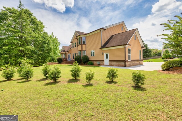 back of house featuring a lawn and concrete driveway