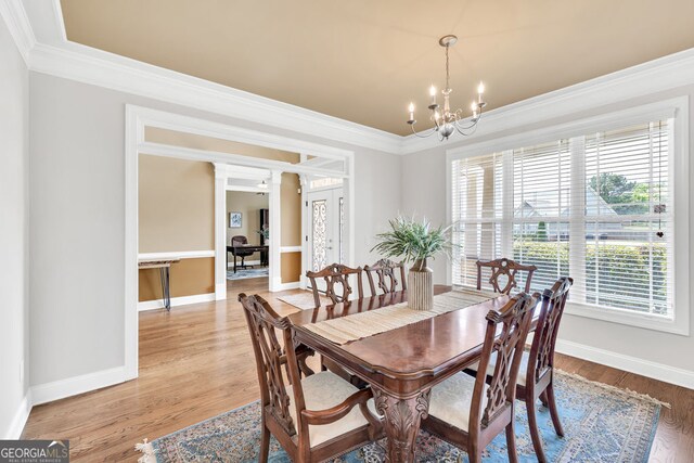 dining area featuring an inviting chandelier, baseboards, ornamental molding, and light wood-type flooring