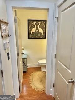 bathroom with baseboards, wood finished floors, and toilet