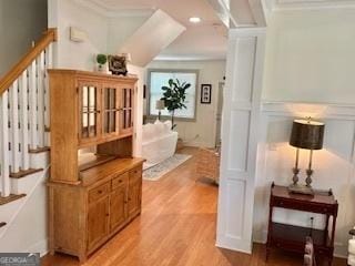 hall featuring stairs, crown molding, and light wood-type flooring