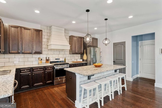 7730 Tiberon Pkwy, Cumming, GA 30028 - kitchen featuring backsplash, dark wood-style flooring, premium range hood, a breakfast bar, and stainless steel appliances